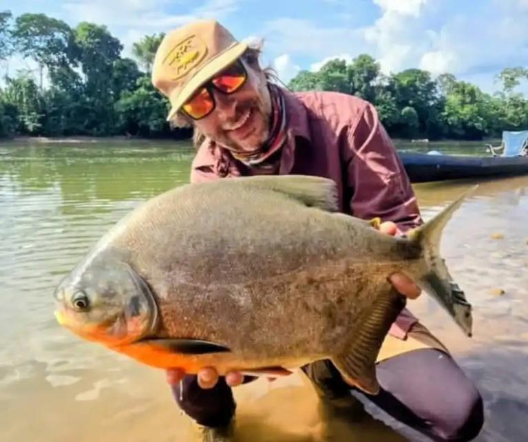 Pescador sorridente segurando uma ótima captura após um dia de pesca desportiva no Peru